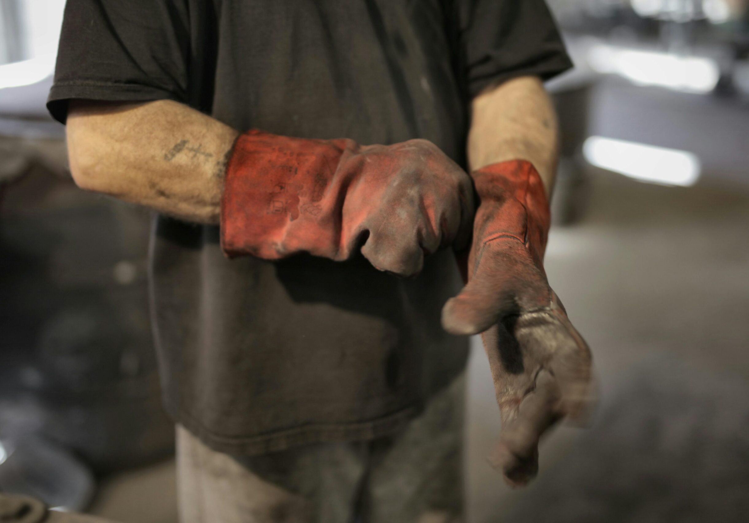 From above of crop male fitter in shabby heavy duty gloves in workshop