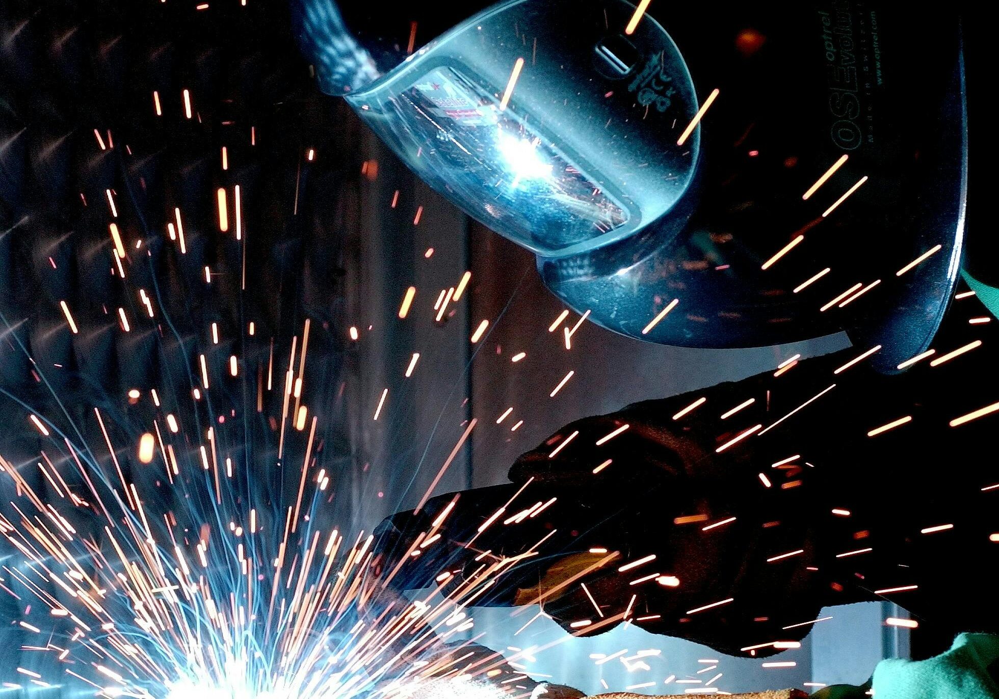 Person in Welding Mask While Welding a Metal Bar